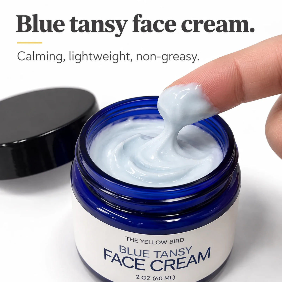 Finger scooping pale blue cream from an open jar of Blue Tansy Face Cream, calming, lightweight and non-greasy