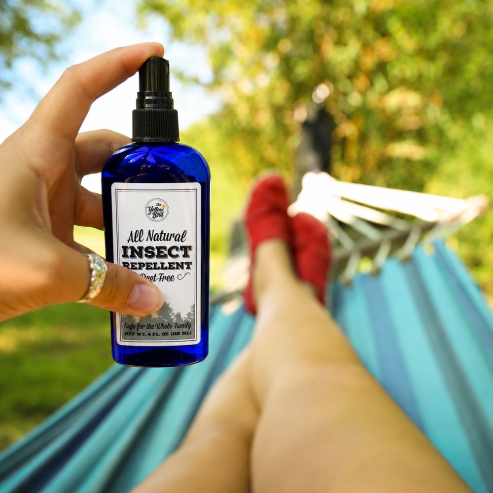 Person holding The Yellow Bird all natural insect repellent while relaxing in hammock outdoors in summer